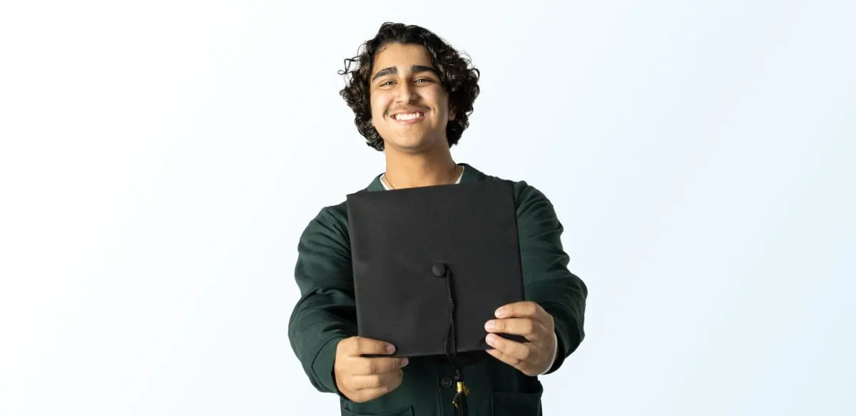 Student smiling holding his graduation hat